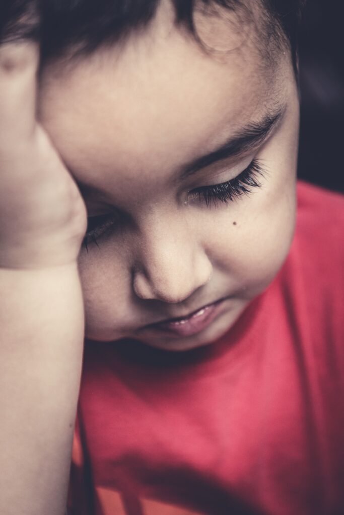 Portrait of a child with hand on forehead, evoking a thoughtful mood.