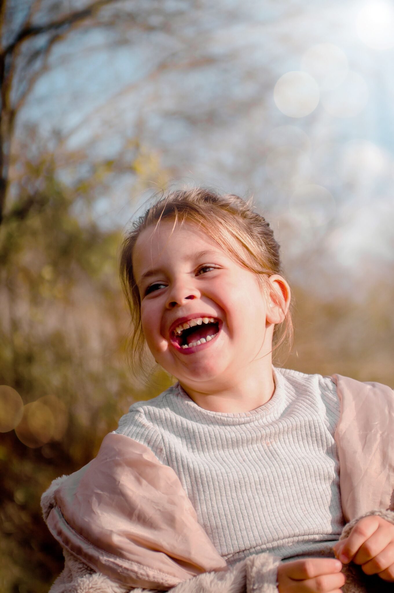 A cheerful child laughing in a sunny outdoor setting, capturing pure joy and happiness.